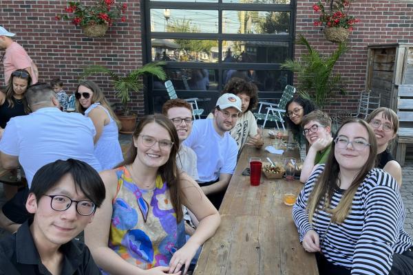 group of graduate students at social even around wooden table