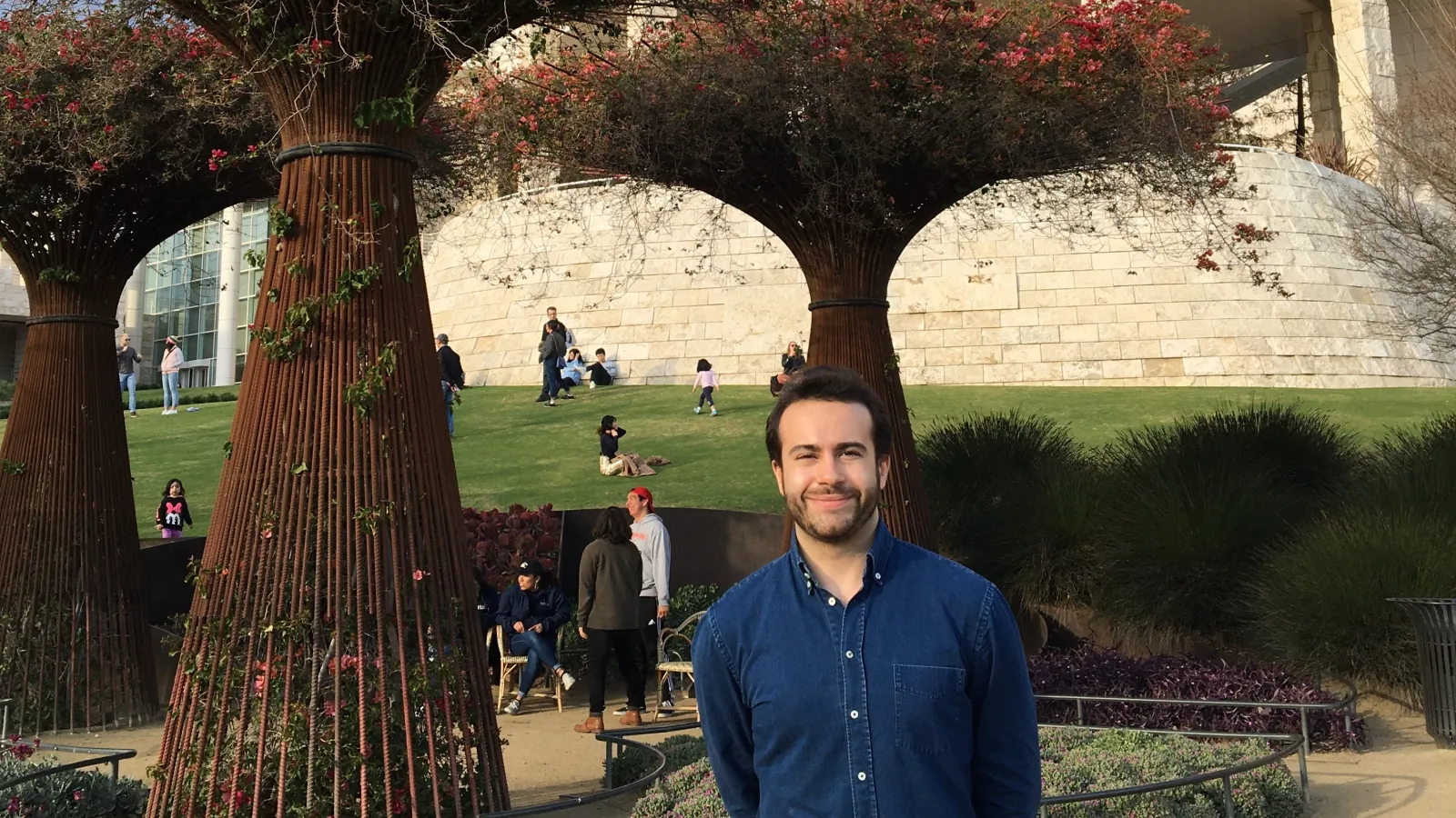 alum Ryan Mitchell standing in front of museum with trees