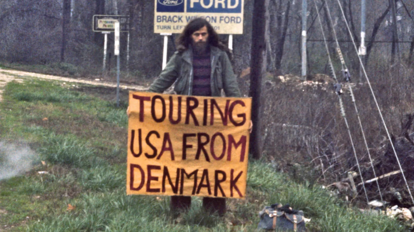 A person holding a sign saying "touring USA from Denmark"