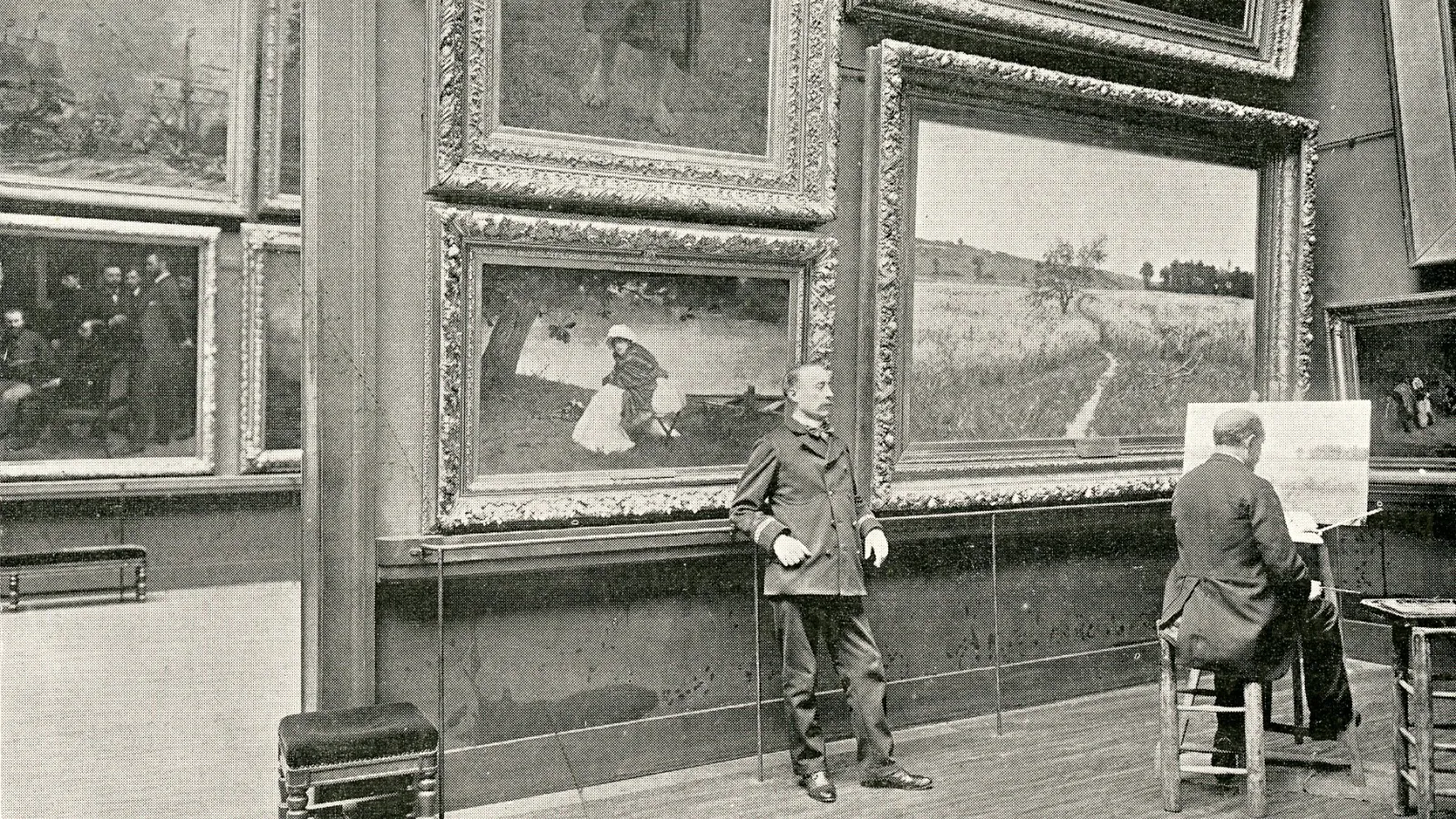a man painting in an art gallery, while another man leans on a wall watching 
