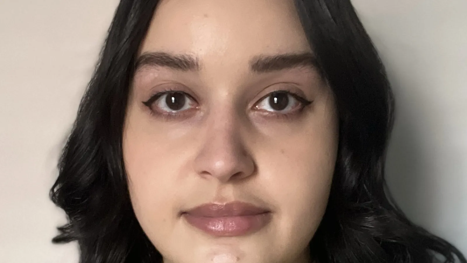 shot of woman facing camera against blank white wall