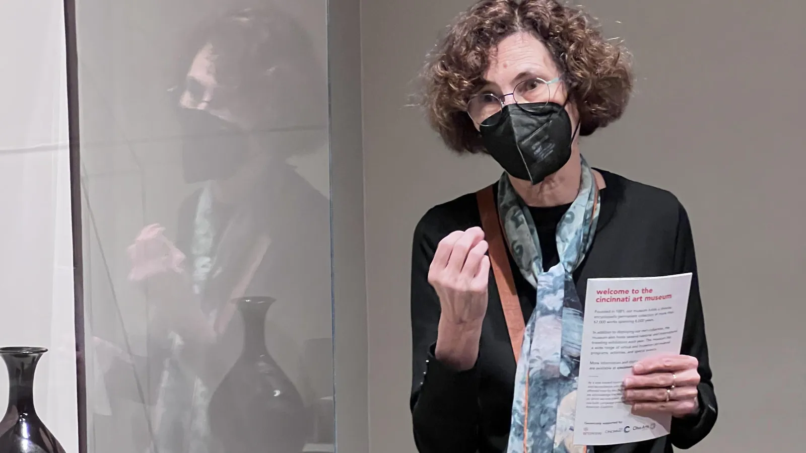 Professor Julia Andrews posing in front of artifact in exhibit