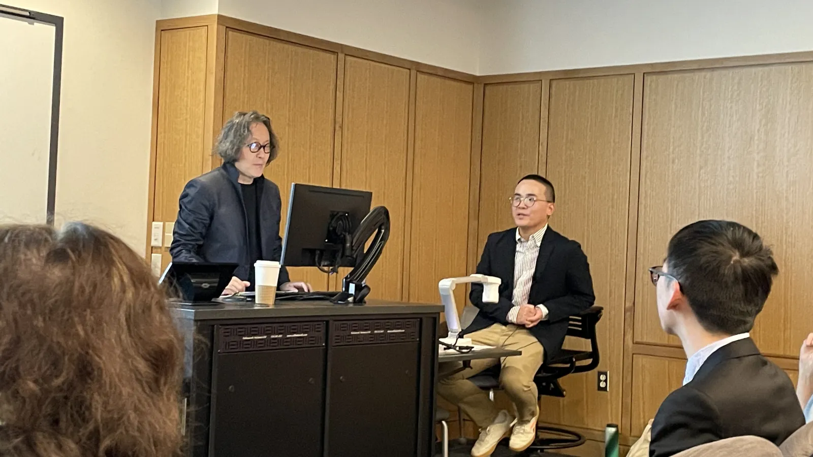 Xi Bing standing at a podium and Yifan Li translating next to him