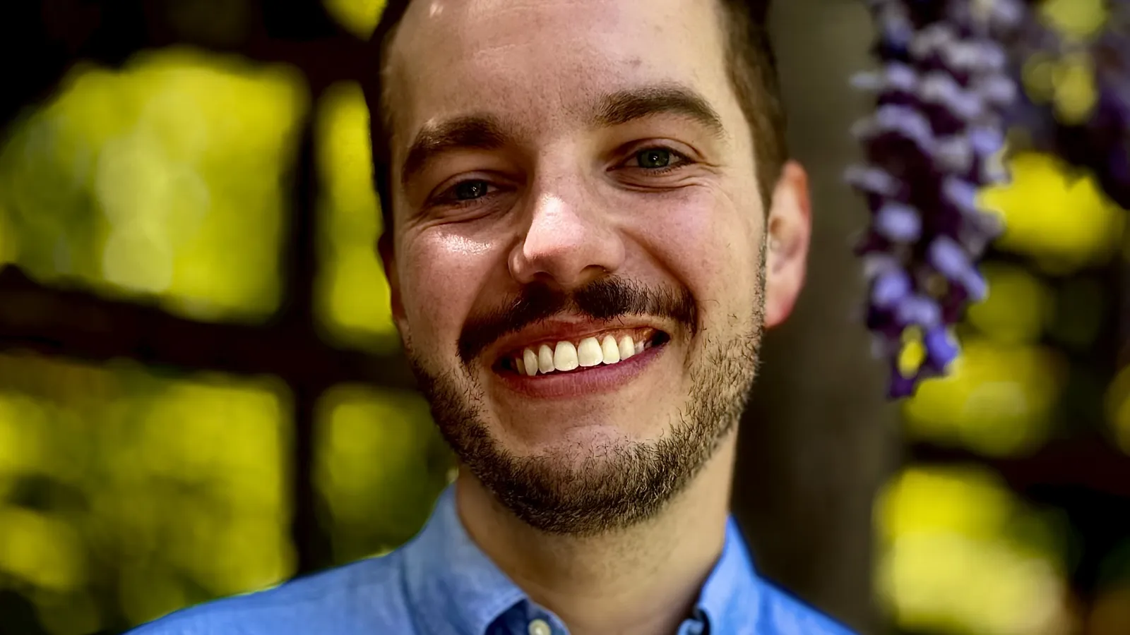 headshot of AJ Meyer, smiling with blue collared shirt against green backgroud