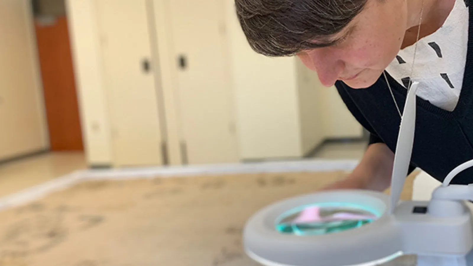 Alanna Radlo-Dzur bending to look closely at a round object