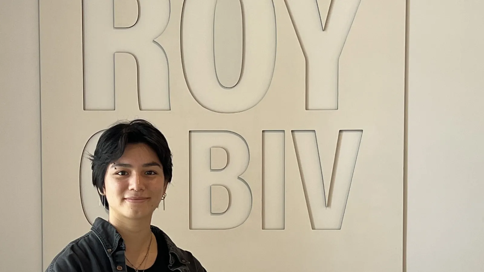 Delia Miklowski standing by ROY G BIV sign