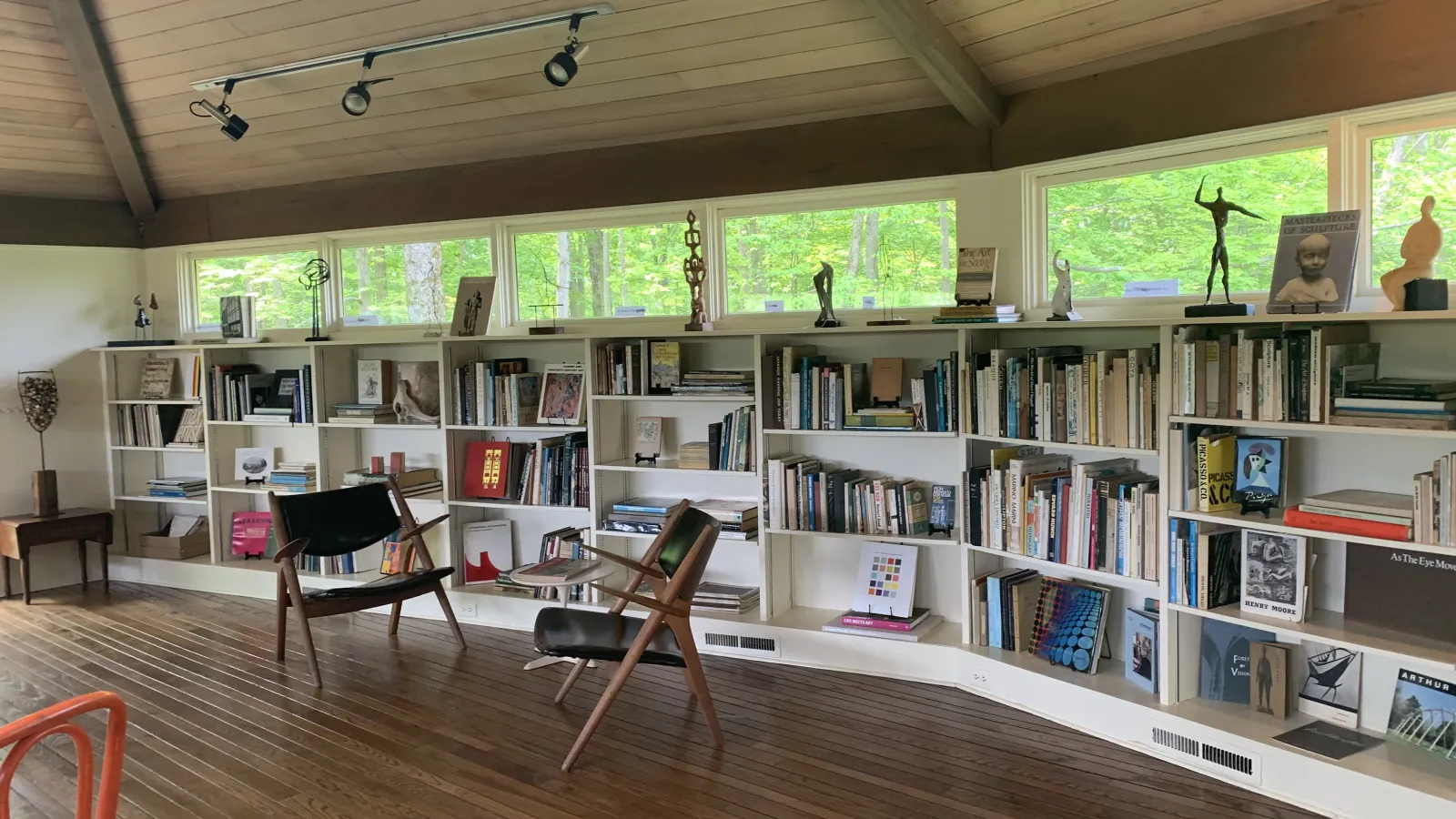 two chairs in front of a big bookshelf in front of windows