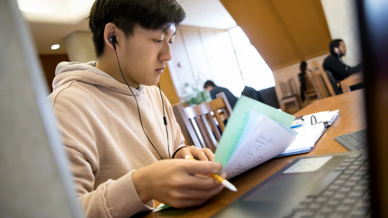 A young man wearing headphones and reading a book.