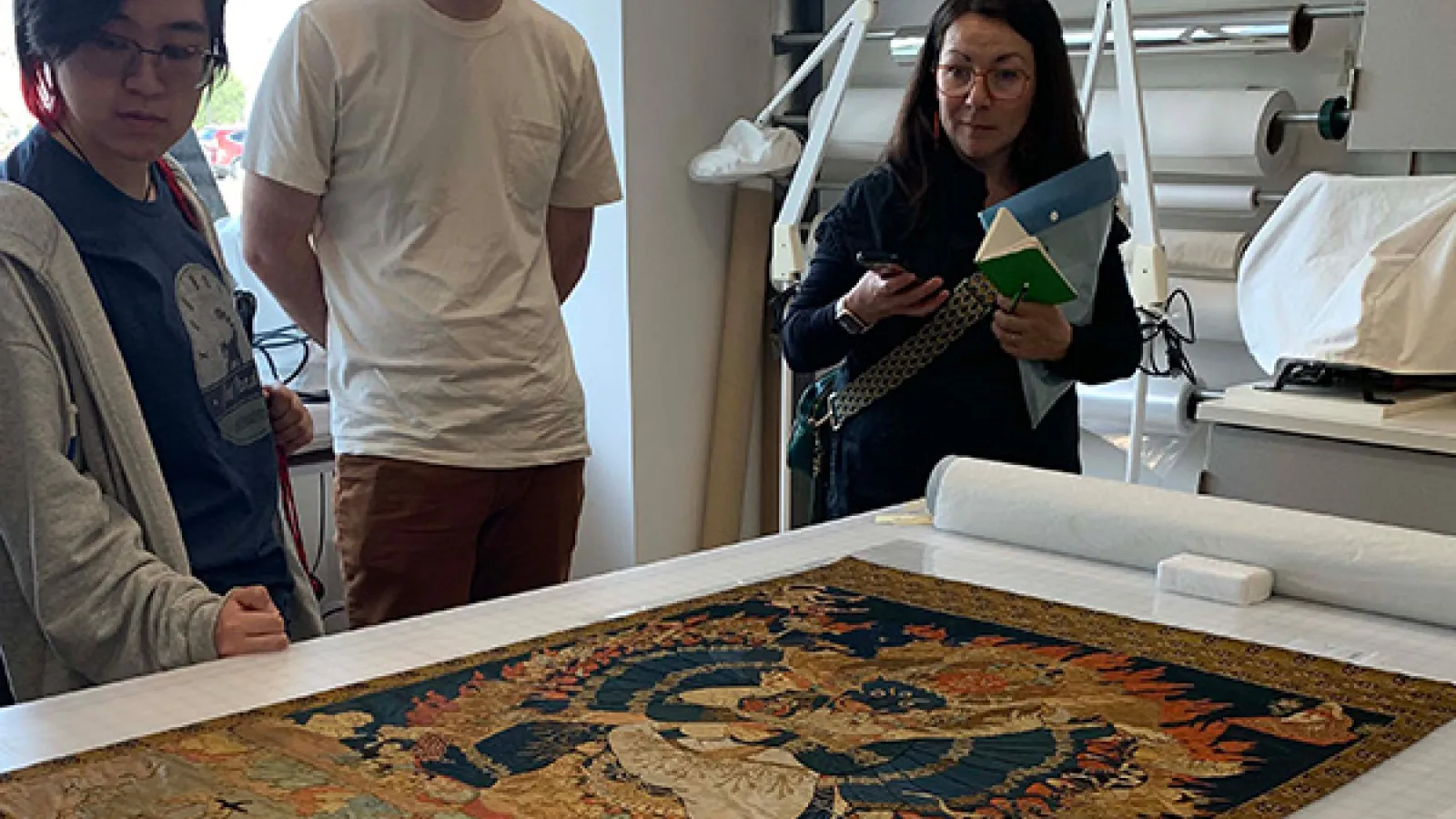 students stand around textile in conservation lab