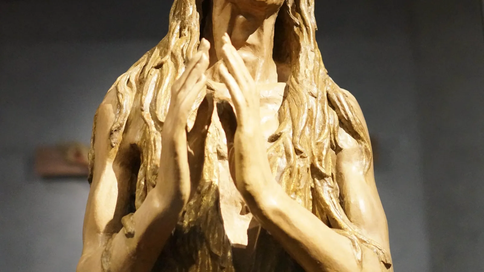 A wooden sculpture of an individual praying