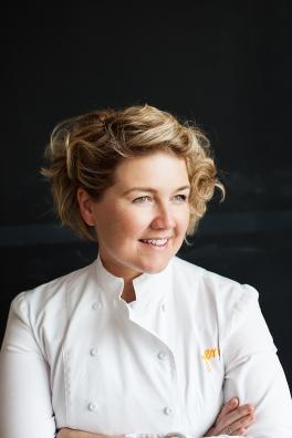 Jeni Britton Bauer headshot, wearing white chef outfit on black background