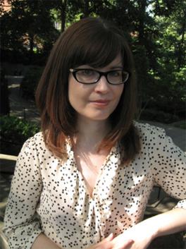 Molly Warnock headshot, light blouse, dark hair, glasses, standing in nature