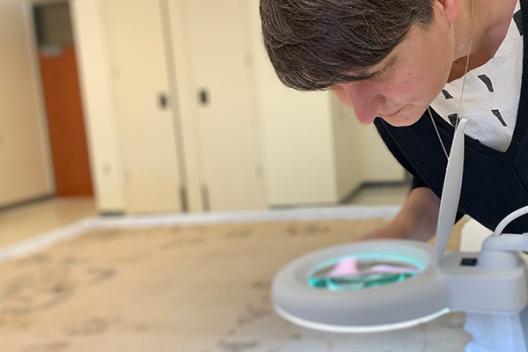 Alanna Radlo-Dzur bending to look closely at a round object