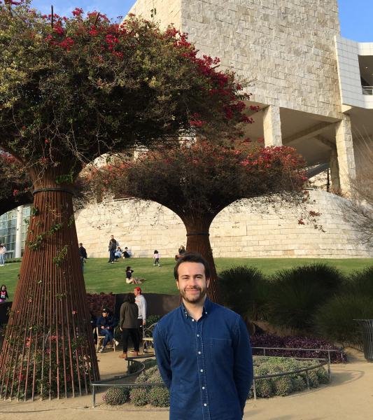 alum Ryan Mitchell standing in front of museum with trees