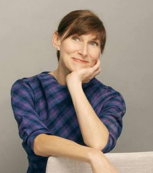 Woman smiling in blue pattern blouse.