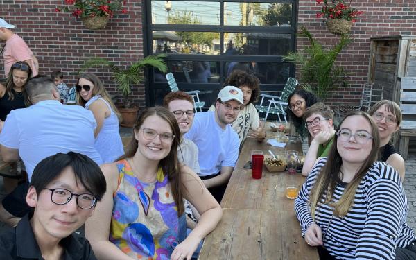group of graduate students at social even around wooden table