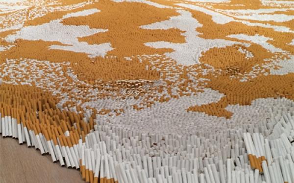 A sculpture by Xu Bing with thousands of cigarettes arranged on the floor to make a pattern