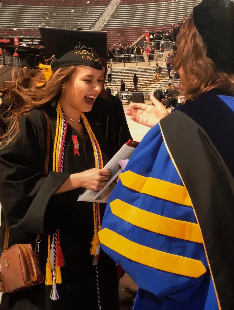 Ana Wong wearing cap and gown and accepting diploma at Graduation 
