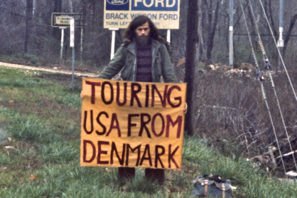 A person holding a sign saying "touring USA from Denmark"