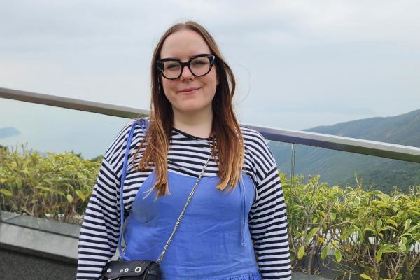 April Riddle Standing outside wearing a blue overall dress and stripped shirt.