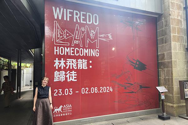 PhD candidate Allie Mickle stands next to a sign for the exhibition Wilfredo Lam: Homecoming