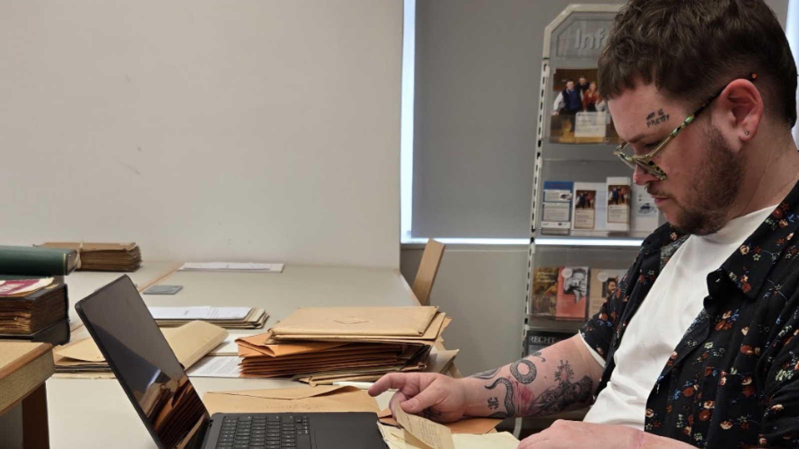 Cole Graham researching at a computer, surrounded by papers.