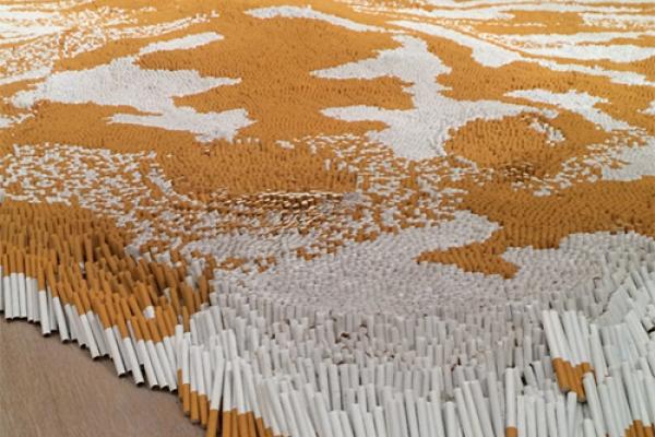 A sculpture by Xu Bing with thousands of cigarettes arranged on the floor to make a pattern