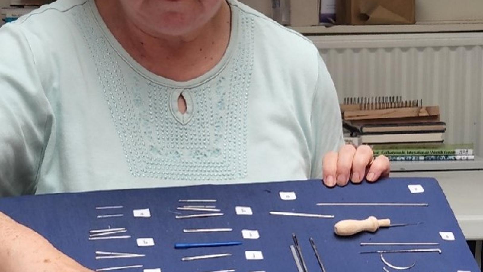 A woman with classes displaying tools used to produce textiles. 