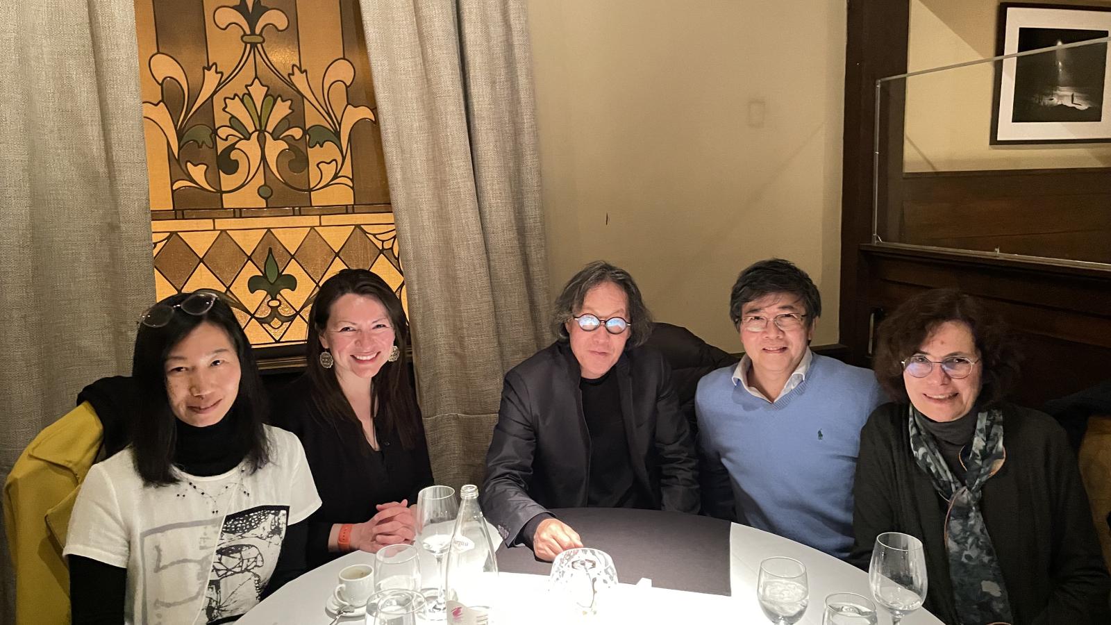 Faculty and staff seated at a table with Xu Bing