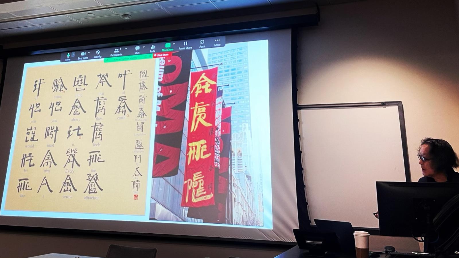 Xu Bing at a podium with his artwork presented on a screen next to him