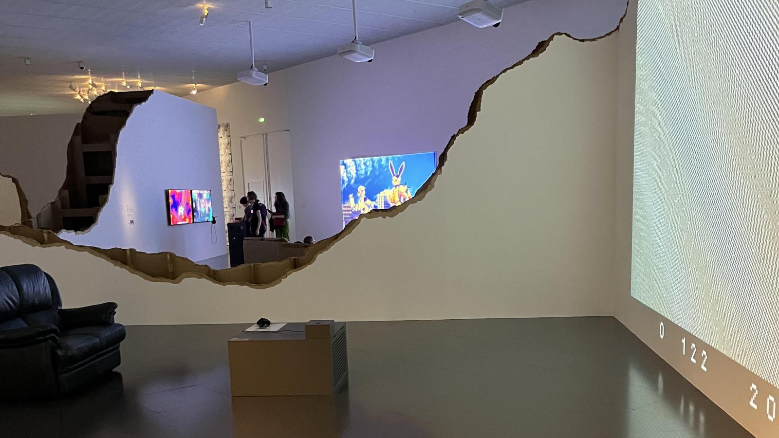 scene of a gallery space with a scalloped wall and video screens