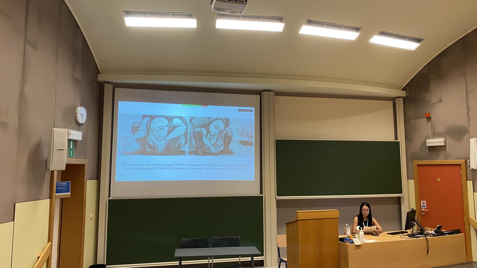 photo of Namiko Kunimoto presenting at the front of a lecture hall 
