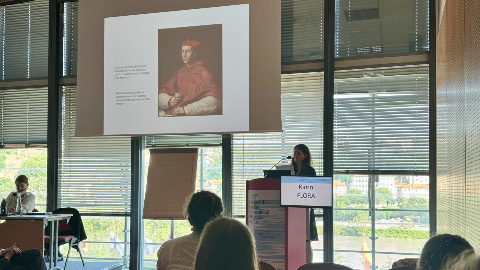 Karin Flora standing at a podium giving a presentation