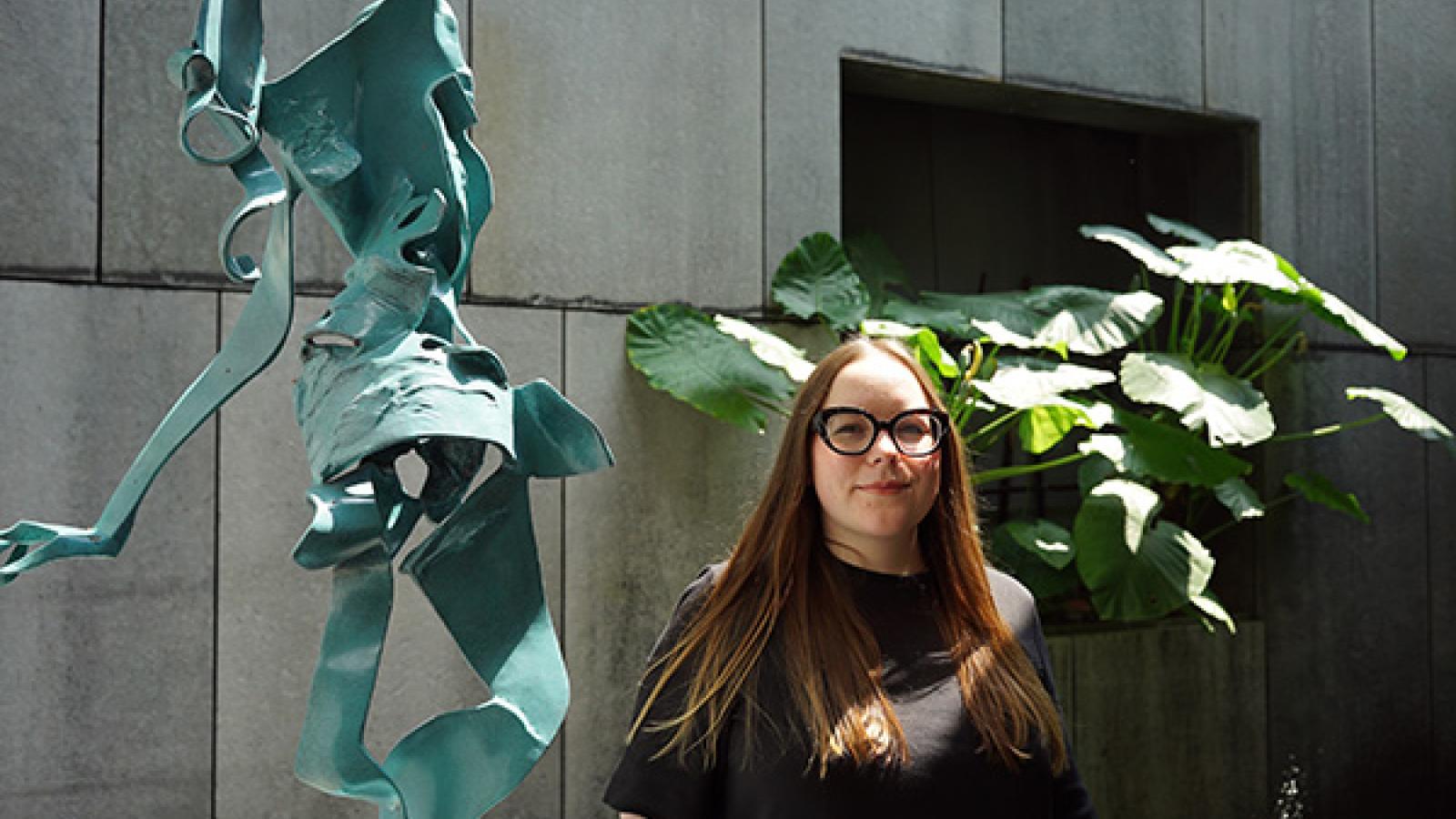 PhD candidate April Riddle stands next to one of Lee Kuang-Yu's sculptures at Asia Society Hong Kong Center
