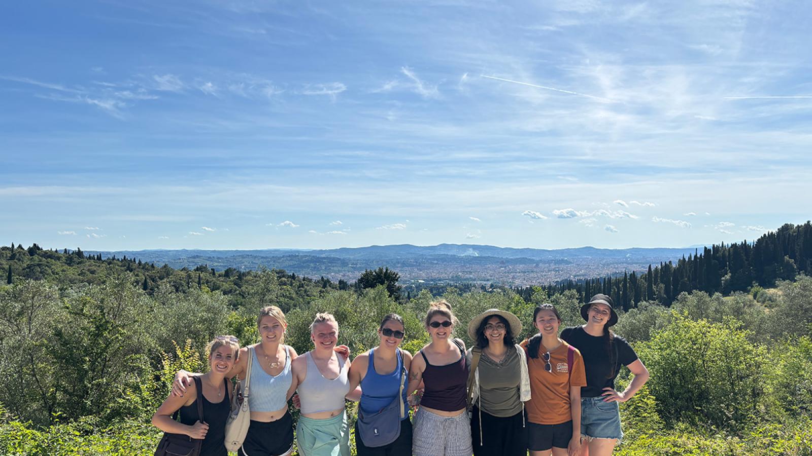 Students in "Medieval Art in Italy" pose for a group photo in front of an Italian landscape
