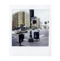 A photo of a street with a car, a mailbox, and a traffic light. 